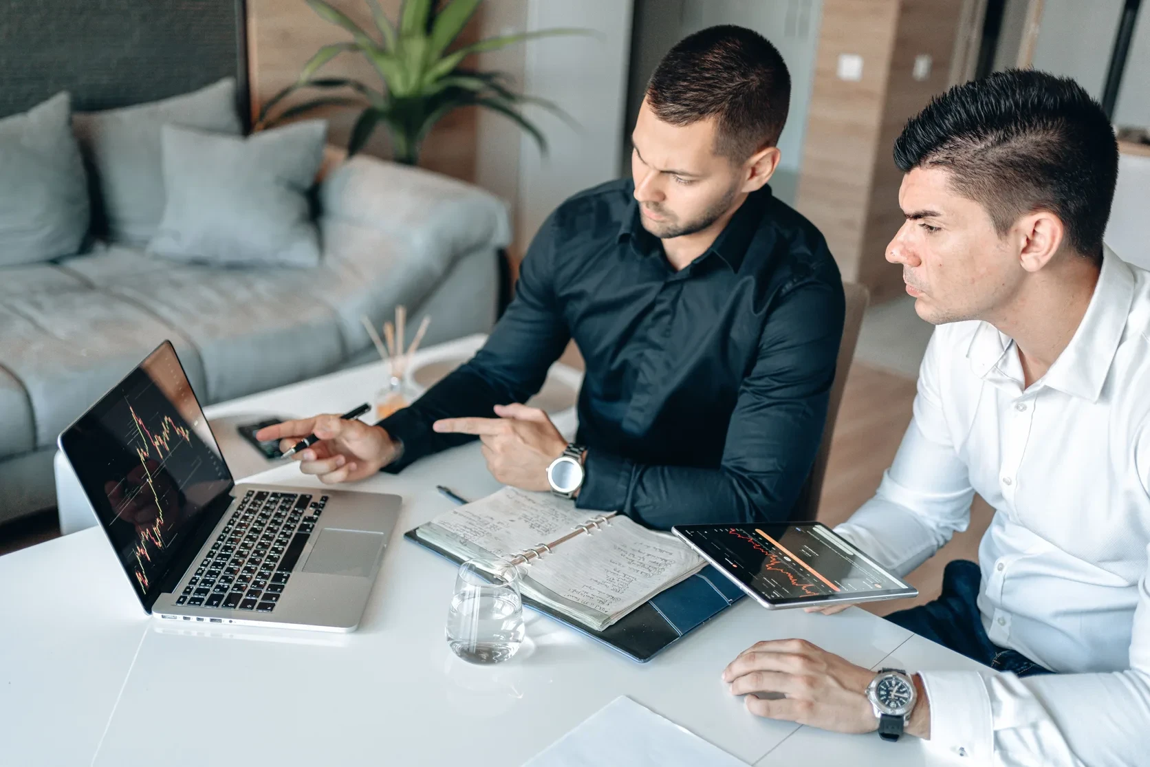Two professionals comparing analytics on a laptop and tablet in a meeting